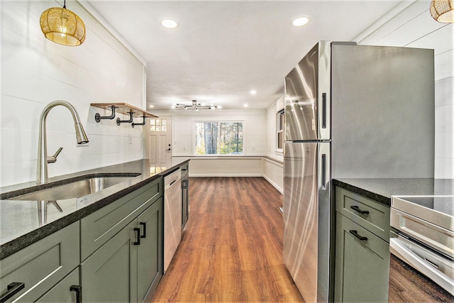 kitchen featuring stainless steel appliances, sink, green cabinetry, decorative light fixtures, and dark hardwood / wood-style flooring