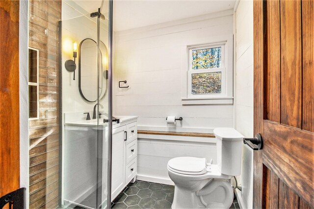 bathroom with wood walls, toilet, walk in shower, tile patterned floors, and vanity