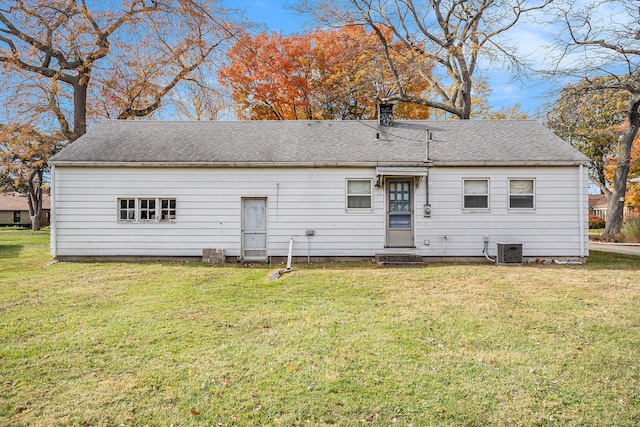 rear view of house with central air condition unit and a yard