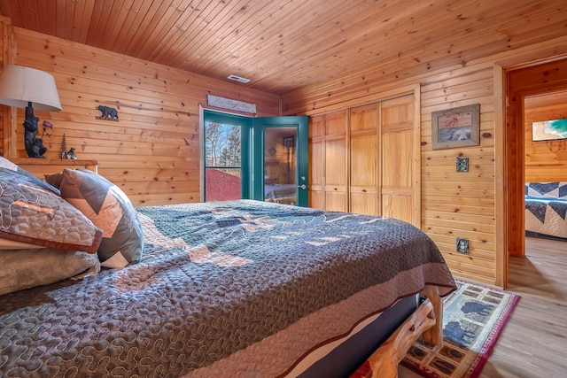 bedroom featuring a closet, wooden walls, wood ceiling, and light hardwood / wood-style flooring