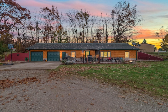 single story home with a porch, a lawn, and a garage