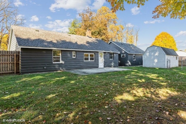 rear view of property featuring a storage shed, a lawn, and a patio