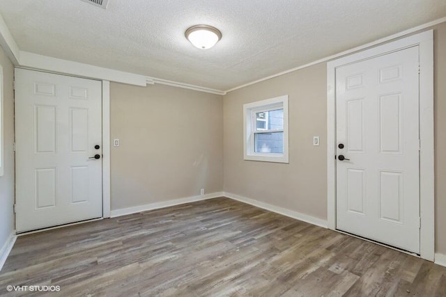 foyer featuring a textured ceiling, light hardwood / wood-style floors, and crown molding