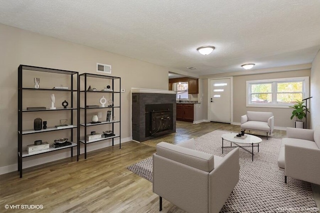 living room featuring light wood-type flooring, a fireplace, and a textured ceiling