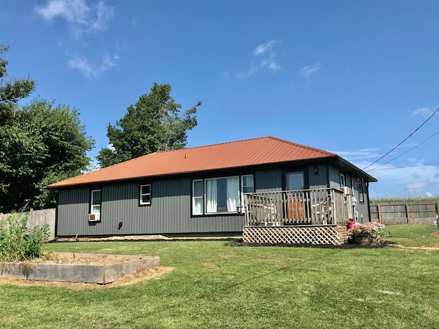 rear view of house featuring metal roof, a lawn, and fence