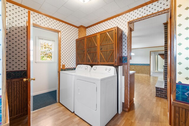 clothes washing area featuring ornamental molding, light wood-type flooring, and washing machine and clothes dryer