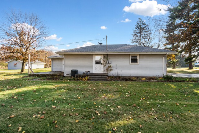 rear view of house featuring cooling unit, a garage, and a lawn