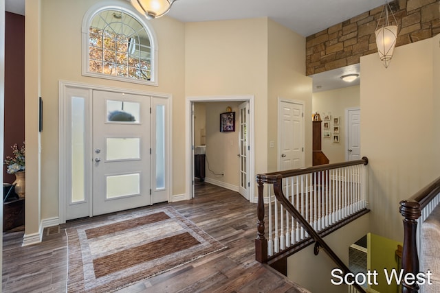 entryway featuring a wealth of natural light, a towering ceiling, and dark wood-type flooring