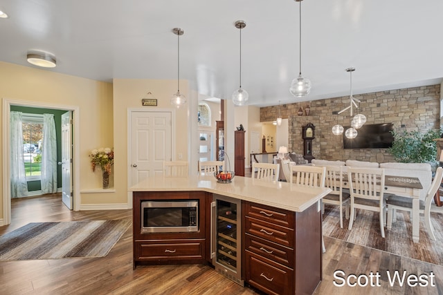 kitchen featuring dark wood-type flooring, a center island, stainless steel microwave, wine cooler, and decorative light fixtures