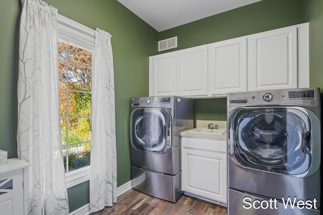 washroom featuring dark hardwood / wood-style flooring, sink, washer and clothes dryer, and cabinets