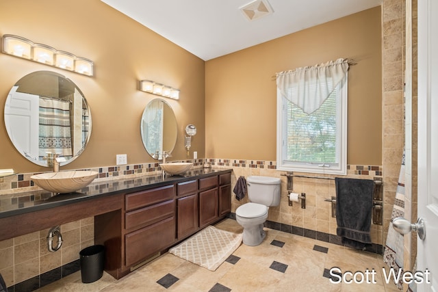 bathroom featuring tile patterned floors, toilet, tile walls, and vanity