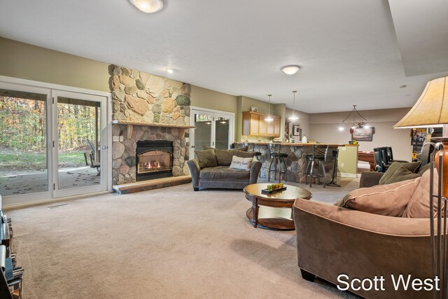 living room featuring a stone fireplace, carpet floors, and indoor bar