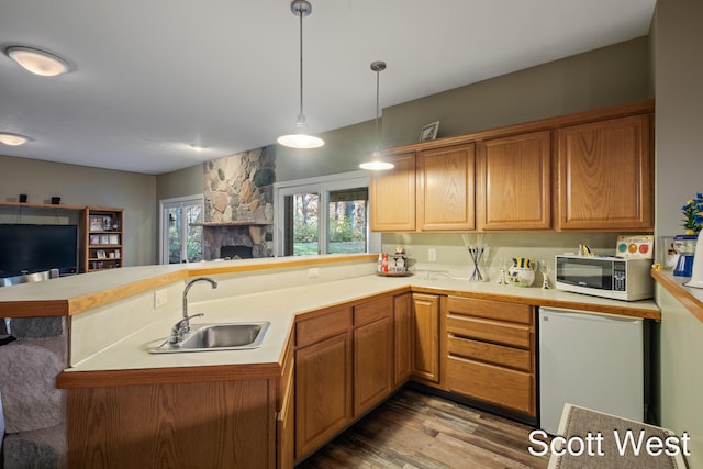 kitchen featuring refrigerator, decorative light fixtures, sink, light hardwood / wood-style floors, and kitchen peninsula