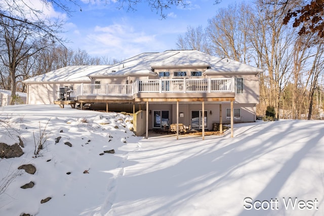 snow covered rear of property with a wooden deck