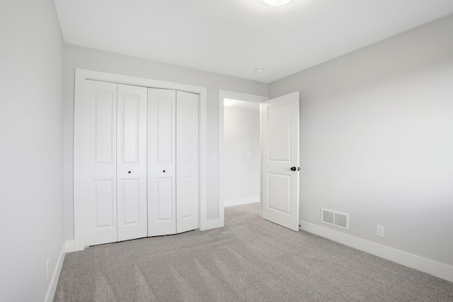 unfurnished bedroom featuring light colored carpet and a closet