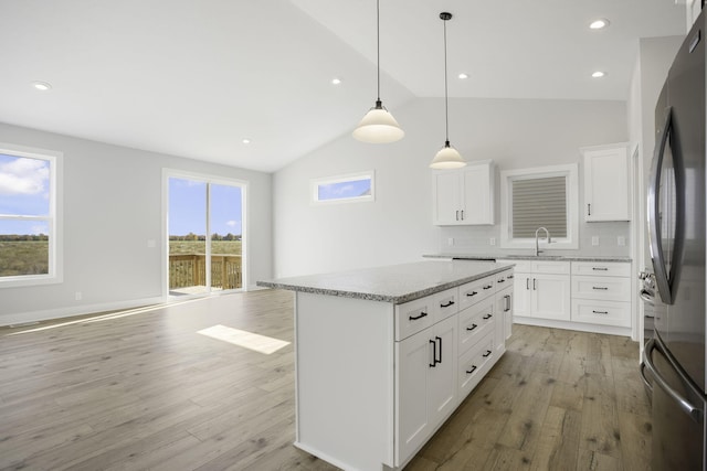 kitchen featuring white cabinetry, a center island, a wealth of natural light, and hanging light fixtures