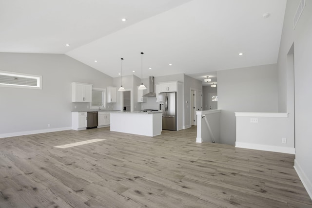 kitchen featuring wall chimney range hood, a kitchen island, appliances with stainless steel finishes, white cabinetry, and pendant lighting