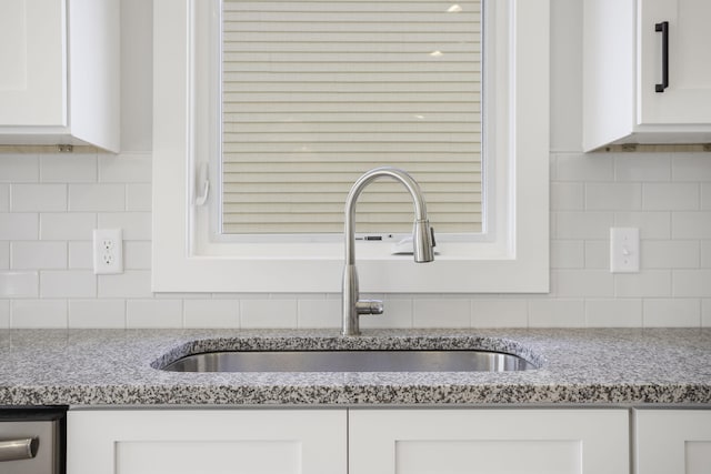 details with decorative backsplash, white cabinets, light stone countertops, and sink