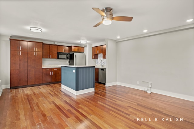 kitchen featuring stainless steel appliances, light hardwood / wood-style floors, sink, ceiling fan, and a kitchen island