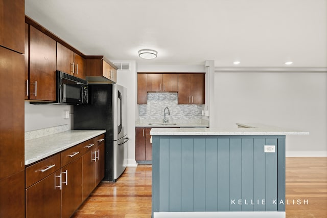 kitchen with light hardwood / wood-style floors, sink, tasteful backsplash, and a center island