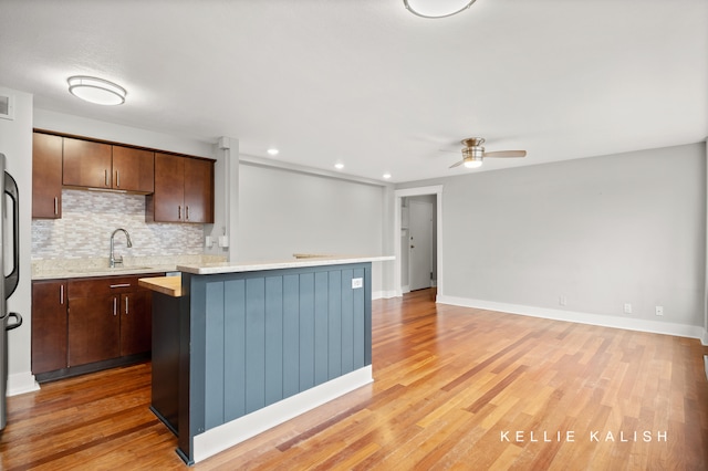 kitchen featuring ceiling fan, dark brown cabinetry, light hardwood / wood-style floors, and a center island