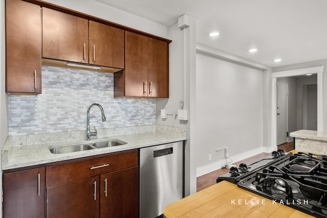 kitchen featuring sink, light stone counters, backsplash, stainless steel dishwasher, and wood-type flooring