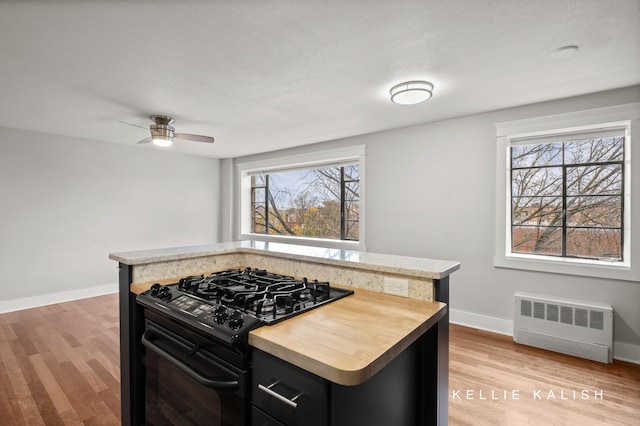 kitchen with a healthy amount of sunlight, radiator heating unit, black gas range, and a kitchen island