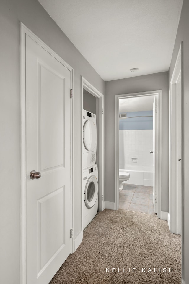 laundry room featuring light carpet and stacked washer / drying machine