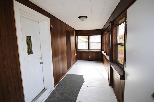 hallway featuring light wood-type flooring and wooden walls