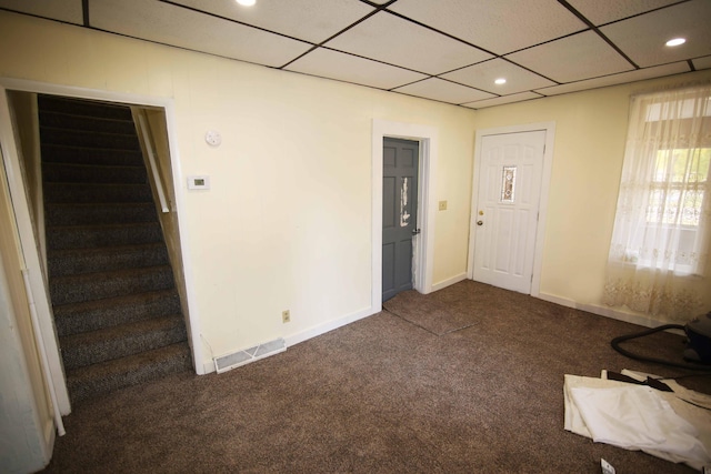 entryway featuring dark colored carpet and a paneled ceiling