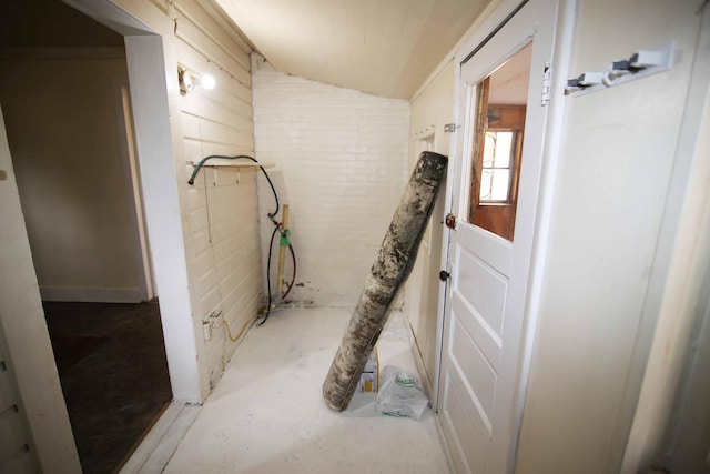 bathroom with brick wall, lofted ceiling, and concrete flooring