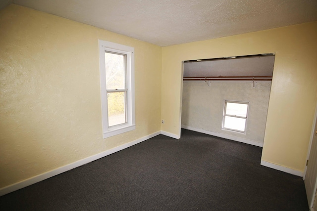 unfurnished bedroom with a closet and dark colored carpet