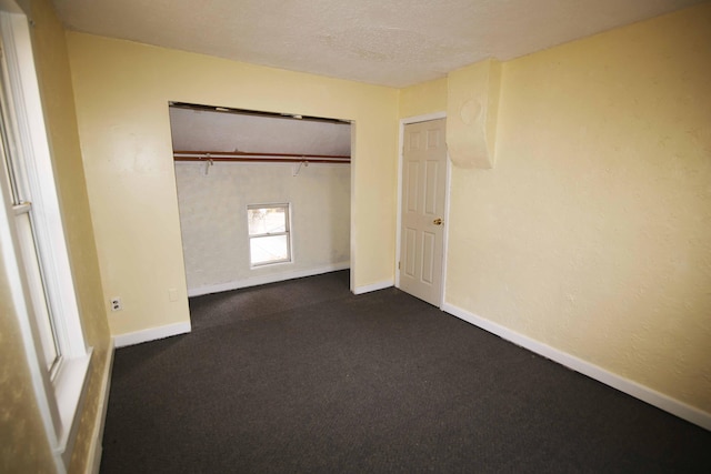 unfurnished bedroom featuring dark colored carpet and a closet