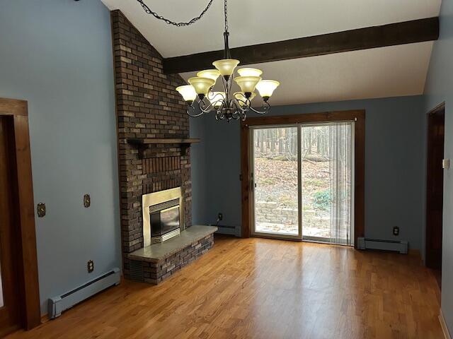 unfurnished living room featuring a baseboard heating unit, vaulted ceiling with beams, wood-type flooring, and an inviting chandelier