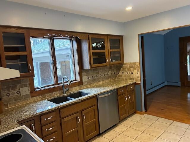 kitchen featuring decorative backsplash, light hardwood / wood-style flooring, sink, light stone countertops, and stainless steel dishwasher