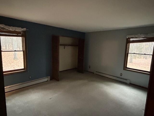 unfurnished bedroom with a closet, baseboard heating, and light colored carpet