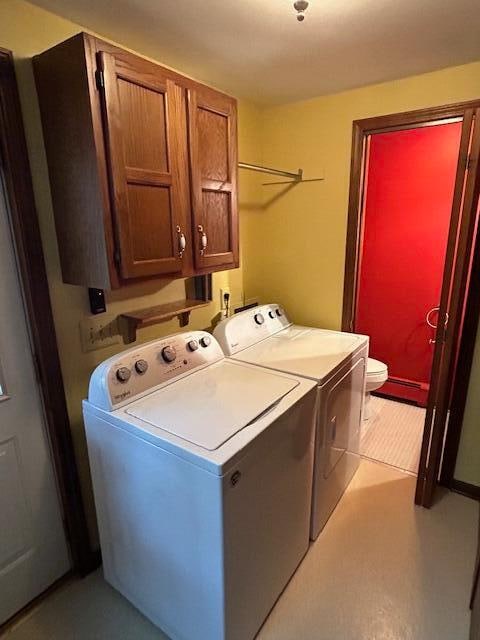 clothes washing area with cabinets and washing machine and dryer