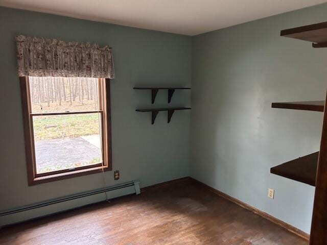 spare room with wood-type flooring and a baseboard heating unit