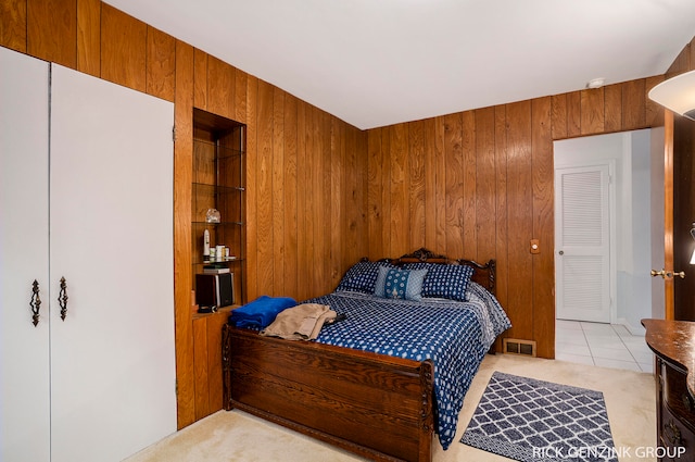 bedroom featuring light carpet and wooden walls