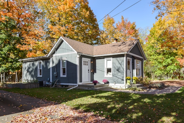 bungalow-style house featuring central air condition unit and a front yard