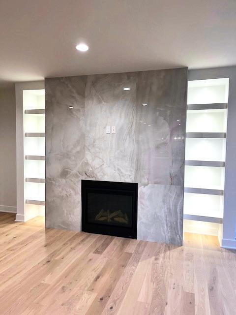 interior details featuring hardwood / wood-style floors, a premium fireplace, and built in shelves