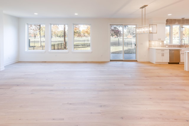 unfurnished dining area with light hardwood / wood-style floors, sink, and an inviting chandelier