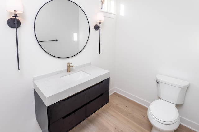 bathroom with toilet, vanity, and wood-type flooring