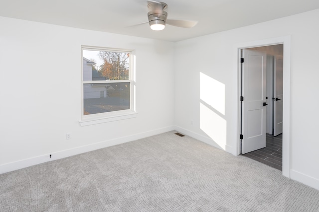 carpeted spare room with ceiling fan