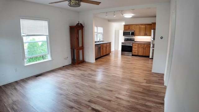 kitchen featuring rail lighting, ceiling fan, sink, light hardwood / wood-style floors, and stainless steel appliances