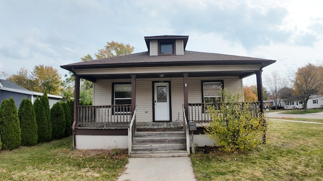 bungalow featuring covered porch and a front yard