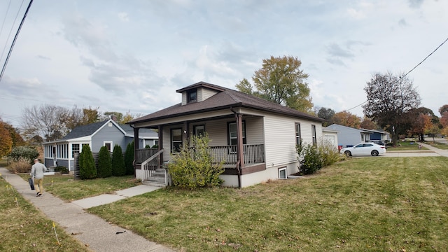 bungalow featuring covered porch and a front yard