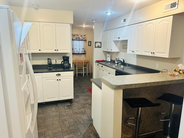 kitchen with sink, a kitchen bar, white refrigerator with ice dispenser, kitchen peninsula, and white cabinetry