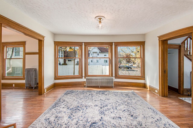 doorway with a textured ceiling, radiator heating unit, and hardwood / wood-style flooring