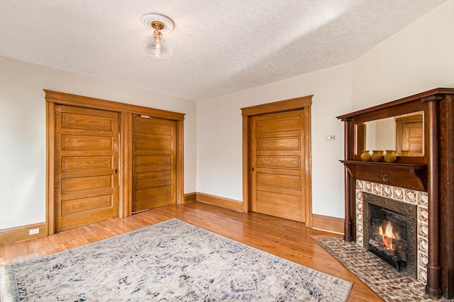 unfurnished living room with a textured ceiling, a fireplace, and light hardwood / wood-style floors